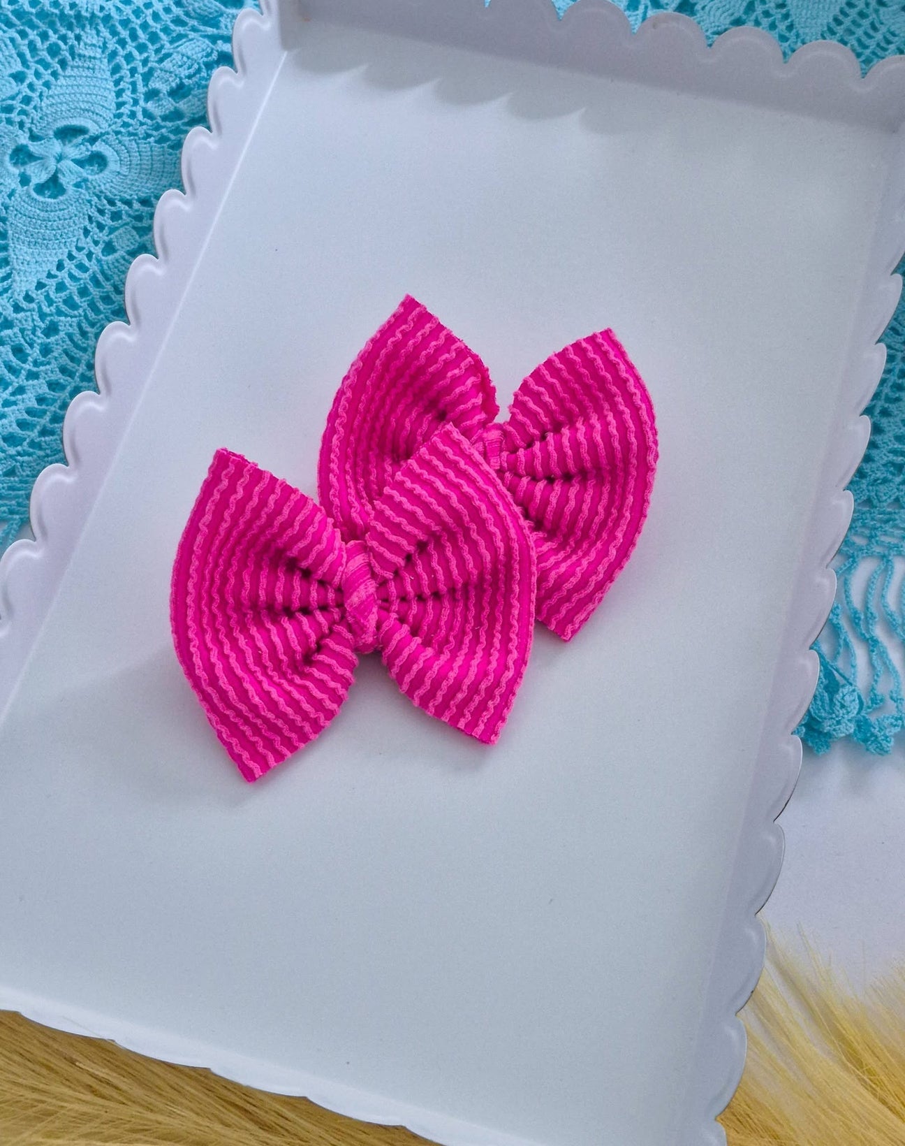 Dark pink piggies set bows on a white tray with a blue lace background.