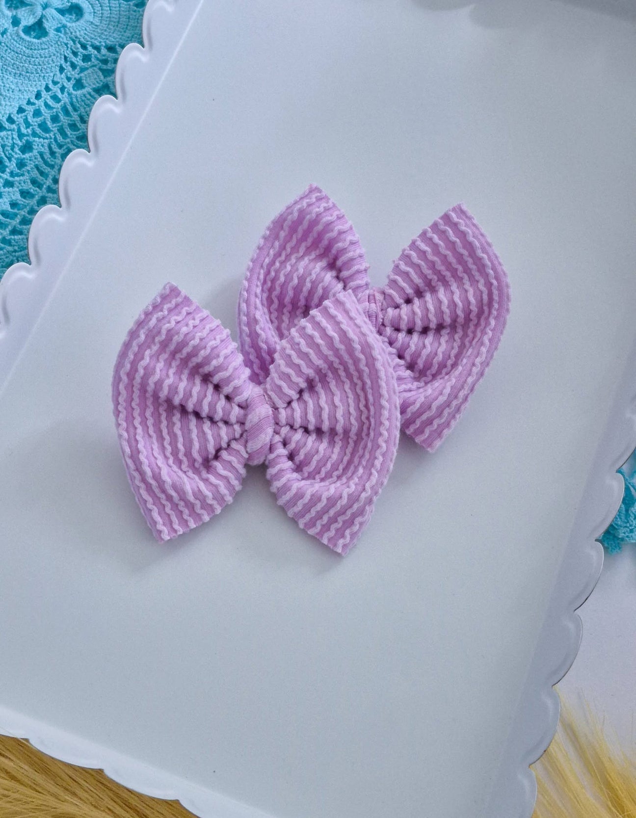 Purple piggies set bows on a white tray with a blue lace background.