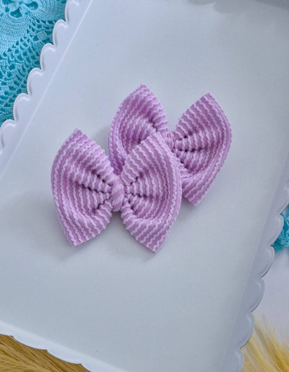 Purple piggies set bows on a white tray with a blue lace background.