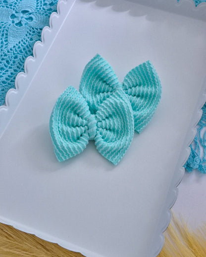 Turquoise piggies set bows on a white tray with a blue lace background.