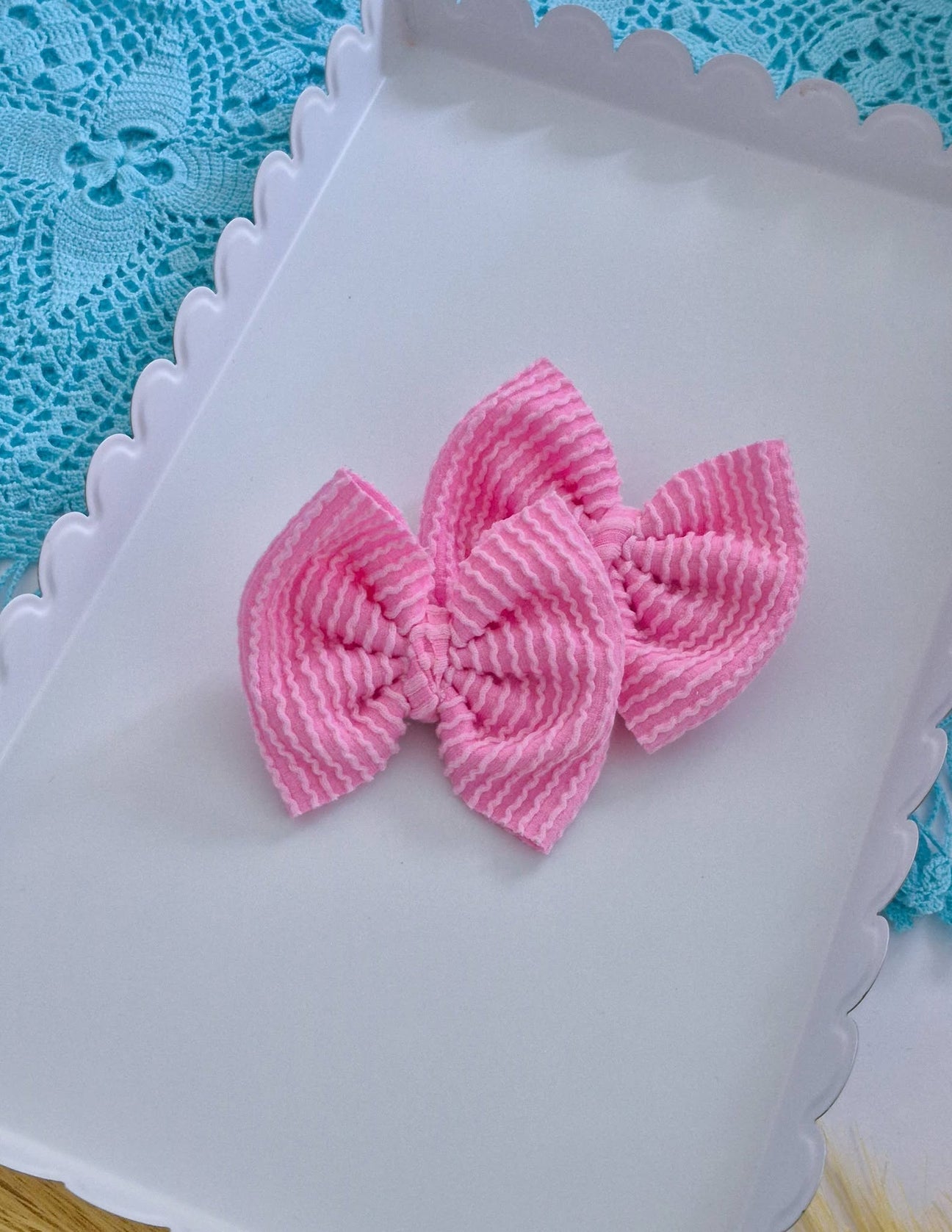 Light pink piggies set bows on a white tray with a blue lace background.