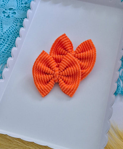 Orange piggies set bows on a white tray with a blue lace background.