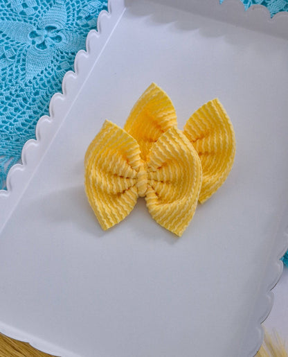 Yellow piggies set bows on a white tray with a blue lace background.