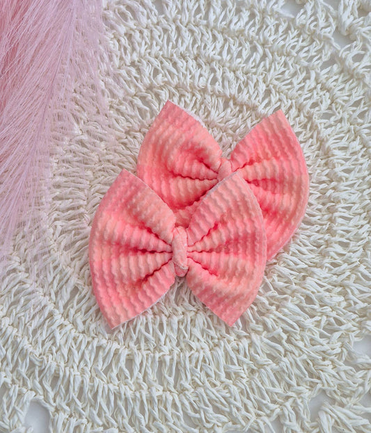 Peach colored piggies set bows on a white lace background.